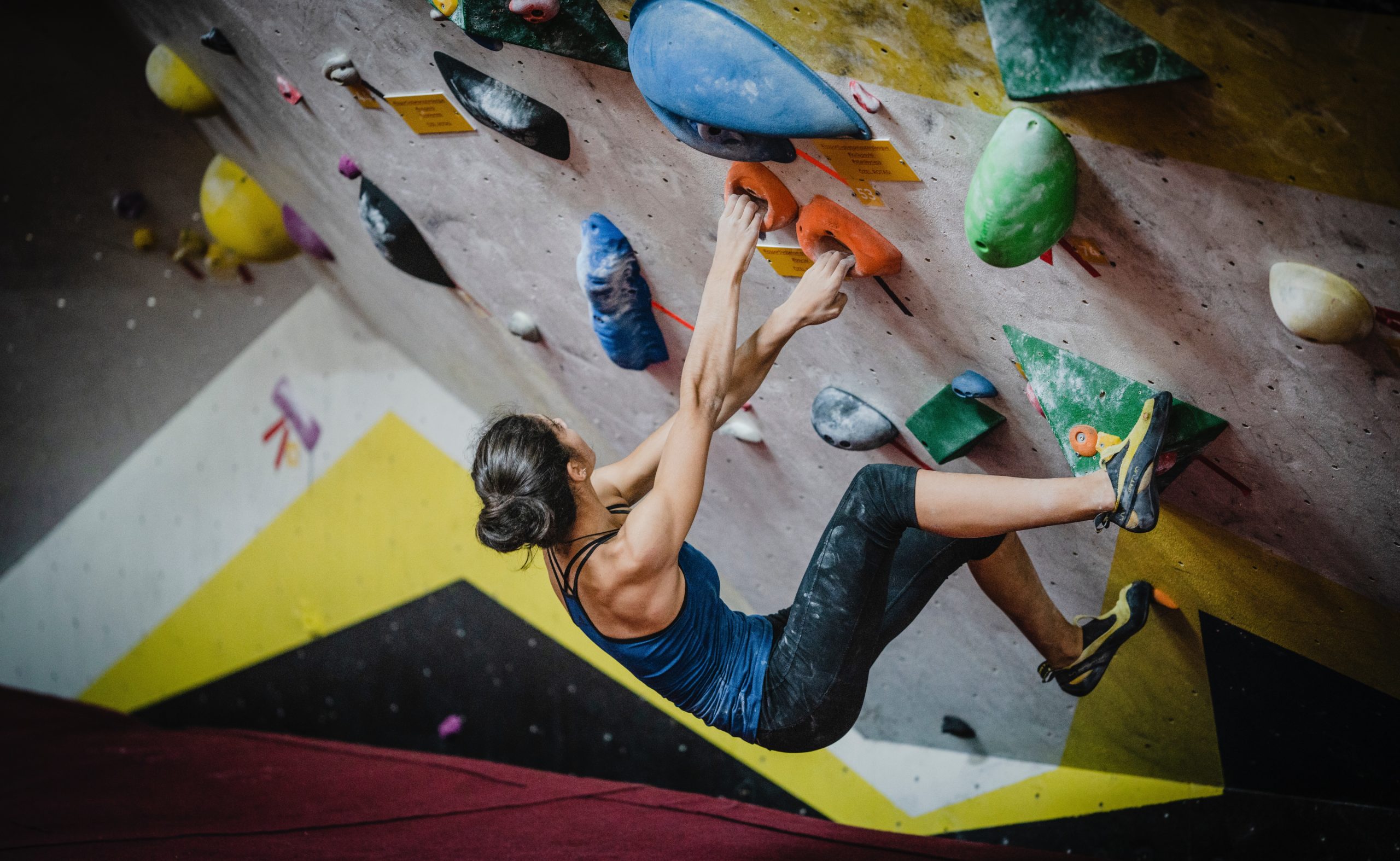 A woman bouldering inside at a gym